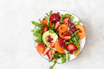 Healthy vegetarian buddha bowl salad with blood orang ,persimmon, arugula, avocado and pomegranate seeds.