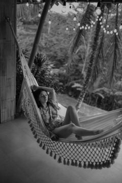 A young female traveller relaxing by a hammock in a jungle hotel in Bali, Indonesia. 
