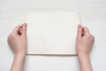 Empty blank photo frame paper sheet with a copy space in the female hands top view background.