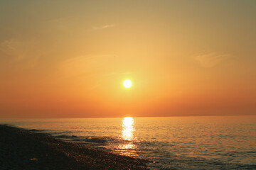 Naklejka na ściany i meble Beautiful sunset on the rocky beach . Soft peaceful water composition