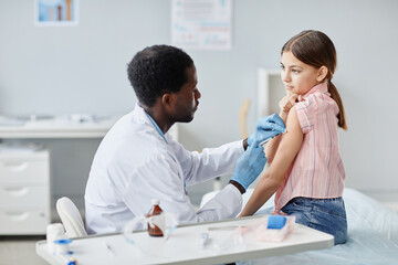Obraz premium Portrait of brave little girl getting vaccinated against COVID - 19 in child vaccination clinic
