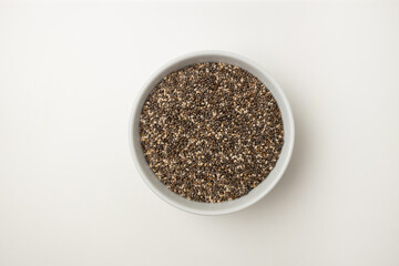 Natural chia seeds in a glass jar with a wooden spoon on a white background, view from above