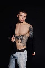 Fototapeta premium Young man with tattoos wearing black shirt on dark background