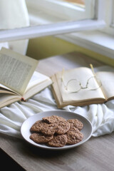 Plate of healthy gluten free cookies, open books and reading glasses on the table. Selective focus.