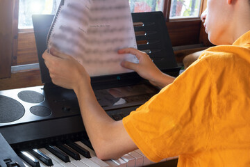 boy practicing playing the piano by reading sheet music