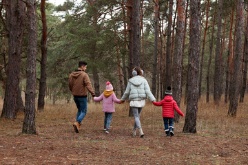Happy family spending time together in forest, back view