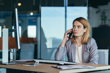 Serious and anxious business woman talking on the phone, working in a modern office at the...