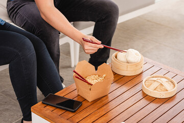 Fototapeta na wymiar pareja irreconocible con comida china en una mesa al aire libre y teléfonos celulares al lado