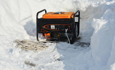 A mobile portable backup generator on the snow after a winter storm. Using a portable generator as an emergency power-supply during black outs in winter snow storms. - obrazy, fototapety, plakaty