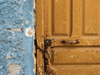 Detalle de una puerta de madera cerrada con una cadena y candado