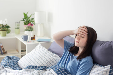 teen girl with headache on bed in white room