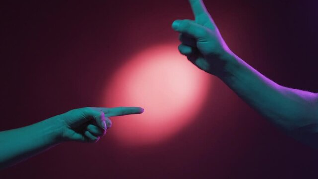 Blaming gesture. Couple accusation. Opposite mind. Male and female hands pointing fingers each other in threaten resistance on red green neon light halo spotlight background.