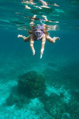 young girl doing snorkeling in crystal clear water