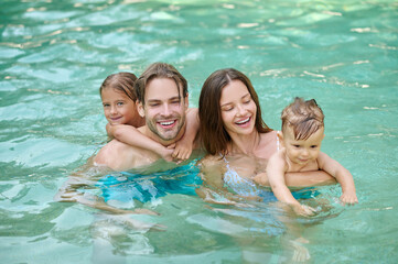 Smiling happy family swimming in a swimming pool