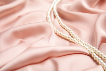 Beautiful pearls on pink silk, space for text