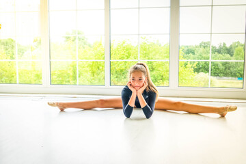 girl in sport bodysuit and ballet shoes making stretching exercise