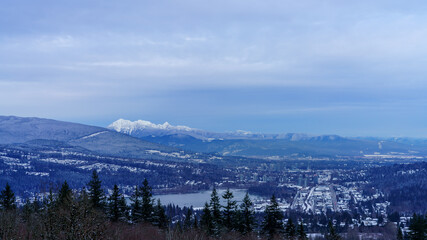 Snow across Fraser Valley, BC, in winter, showing town of Port Moody at Burrard Inlet, with alpine mountain backdrop.