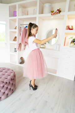 Teen girl in tutu-skirt and high-heeled shoes making selfie on smartphone