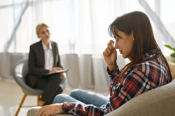 Woman crying crumpling napkins talking to psychologist