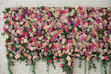 Beautiful decorative colorful roses and peonies on brick white wall. Interior wedding party decor....