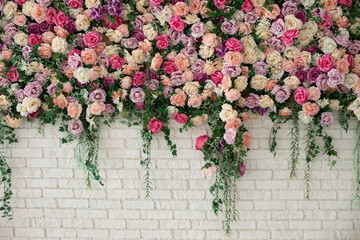Beautiful decorative colorful roses and peonies on brick white wall. Interior wedding party decor....
