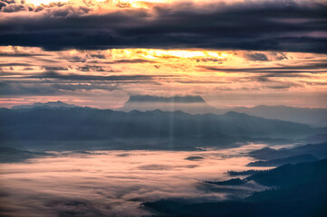 Fototapeta premium Scenery of golden sunrise over Doi Luang Chiang Dao mountain with sunbeam and foggy in the valley at morning