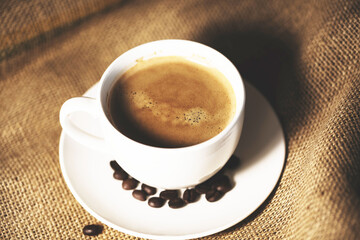 Cup of coffee with coffee beans on coffee sack