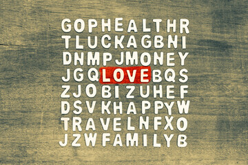 Love word in crossword puzzle game arranged with wooden alphabets on wood board, with some hidden...