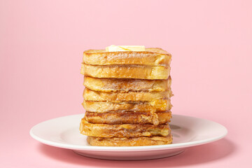 eggy bread on a pink background. Butter melts on a stack of eggy breads. Tasty breakfast.