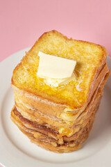 eggy bread on a pink background. Butter melts on a stack of eggy breads. Tasty breakfast.
