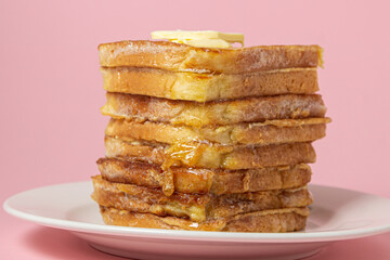 eggy bread on a pink background. Butter melts on a stack of eggy breads. Tasty breakfast.