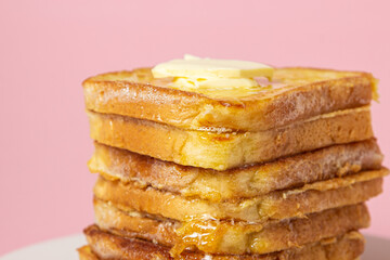 eggy bread on a pink background. Butter melts on a stack of eggy breads. Tasty breakfast.