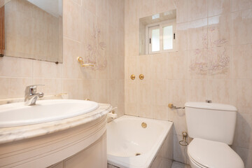 Fototapeta na wymiar Bathroom tiled with cream tiles with white marble top and bathtub