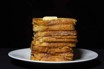 eggy bread on a black background. Butter melts on a stack of eggy breads. Tasty breakfast.