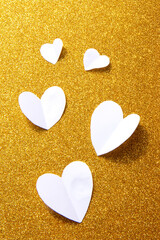 Obraz premium Valentine's Day background. White volumetric paper hearts on golden background. Valentine's Day concept. Vertical flat lay
