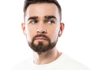 Obraz premium Handsome bearded man in white clothes using wireless earbuds on white background