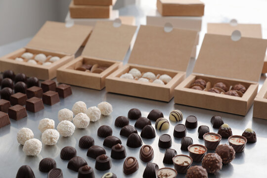 Different delicious chocolate candies and boxes on white table. Production line