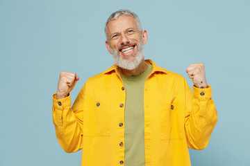 Elderly gray-haired mustache bearded man 50s wear yellow shirt doing winner gesture celebrate...