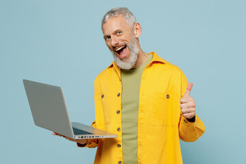 Elderly fun happy gray-haired mustache bearded man 50s in yellow shirt hold use work on laptop pc...