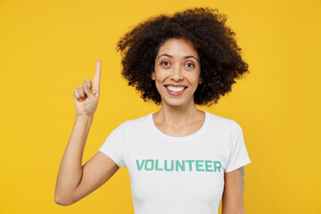 Young woman of African American ethnicity in white volunteer t-shirt holding index finger up with...