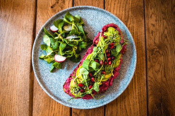 Vegan sandwich with beet spread and lamb's lettuce on a wooden table. Healthy vegan food in coffee shop. Detox diet.