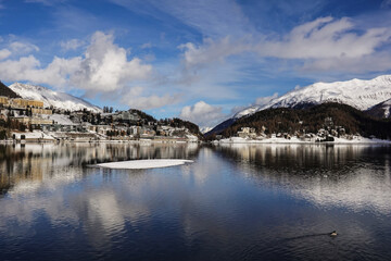 Dramatic reflection of the Saint Moritz famous village in the lake on a sunny winter day in Canton Graubunden in the alps in Switzerland