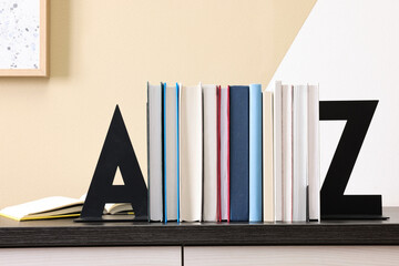Minimalist letter bookends with books on table indoors - obrazy, fototapety, plakaty