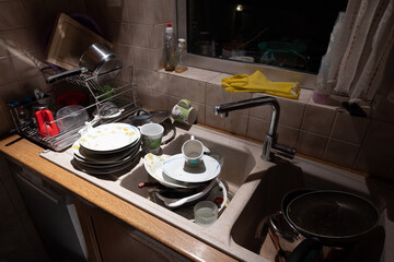 Lot of dishes for washing in the sink of a home kitchen.