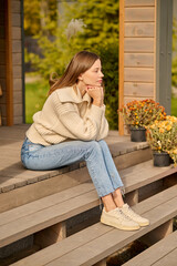 Woman sitting on porch of house sideways to camera