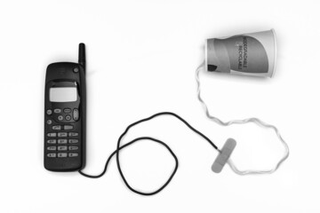 Teléfono móvil conectado por un cable a un vaso de papel reciclado. Fotografía conceptual en...
