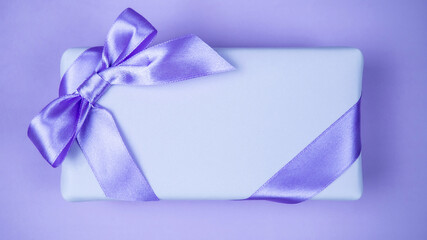 Gift box with a bow. Lilac and purple background. Celebration.