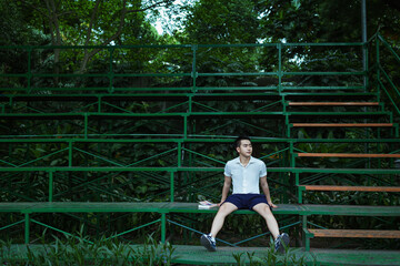 student boy with white shirt, blue short is studying in green park