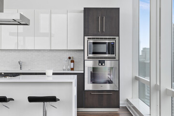 Fototapeta premium Modern Luxury Kitchen in Penthouse Apartment with Stainless Steel Appliances, Waterfall Countertops, Two Toned Cabinets