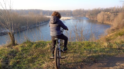 7 years old boy child drives a bicycle in nature wood near the river in Ticino natural park , Pavia...